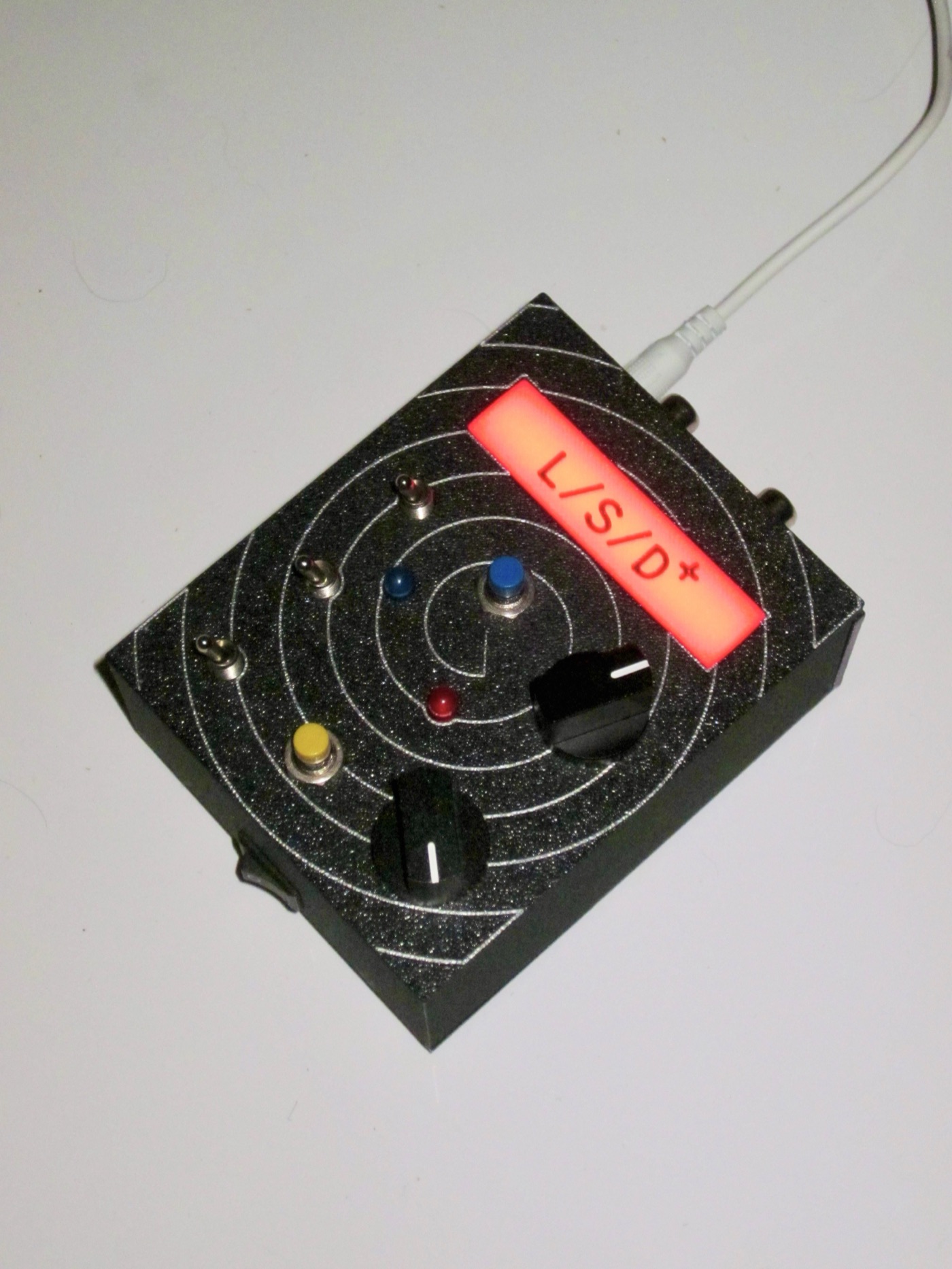 Orbit-pattern unit, red backlight, showing the RCA jack side